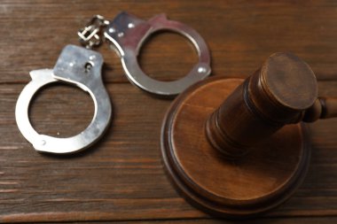 Hukuk konsepti, açık hukuk kitabı, yargıç tokmağı, teraziler, mahkeme salonundaki ya da kolluk kuvvetlerindeki kelepçeler. Tahta masa, beyaz arkaplan.