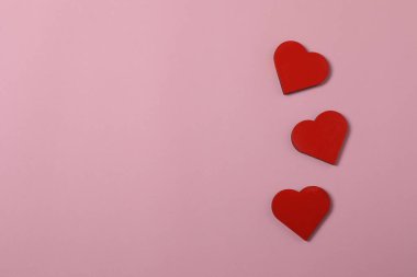 Kırmızı kurdelelere sarılı, pembe arka planda kırmızı kalplerle çevrili sevgililer günü afişi. Romantik ve şenlikli etkinlikler için ideal.