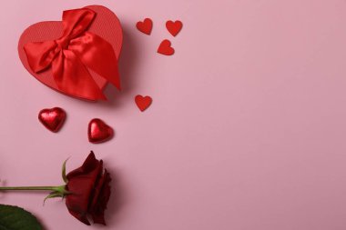 Kırmızı kurdelelere sarılı, pembe arka planda kırmızı kalplerle çevrili sevgililer günü afişi. Romantik ve şenlikli etkinlikler için ideal.