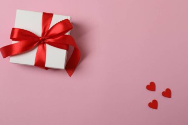 Kırmızı kurdelelere sarılı, pembe arka planda kırmızı kalplerle çevrili sevgililer günü afişi. Romantik ve şenlikli etkinlikler için ideal.