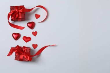 Kırmızı kurdelelere sarılı, beyaz arka planda kırmızı kalplerle çevrili sevgililer günü afişi. Romantik ve şenlikli etkinlikler için ideal.