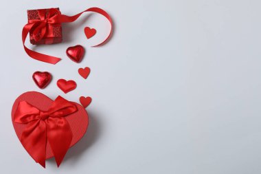 Kırmızı kurdelelere sarılı, beyaz arka planda kırmızı kalplerle çevrili sevgililer günü afişi. Romantik ve şenlikli etkinlikler için ideal.