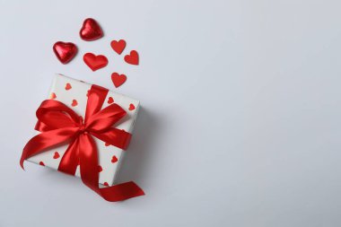 Kırmızı kurdelelere sarılı, beyaz arka planda kırmızı kalplerle çevrili sevgililer günü afişi. Romantik ve şenlikli etkinlikler için ideal.