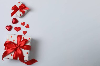 Kırmızı kurdelelere sarılı, beyaz arka planda kırmızı kalplerle çevrili sevgililer günü afişi. Romantik ve şenlikli etkinlikler için ideal.