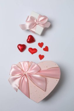 Kırmızı kurdelelere sarılı, beyaz arka planda kırmızı kalplerle çevrili sevgililer günü afişi. Romantik ve şenlikli etkinlikler için ideal.