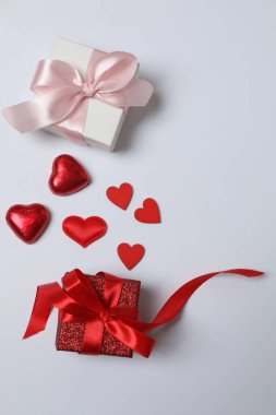 Kırmızı kurdelelere sarılı, beyaz arka planda kırmızı kalplerle çevrili sevgililer günü afişi. Romantik ve şenlikli etkinlikler için ideal.