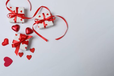 Kırmızı kurdelelere sarılı, beyaz arka planda kırmızı kalplerle çevrili sevgililer günü afişi. Romantik ve şenlikli etkinlikler için ideal.