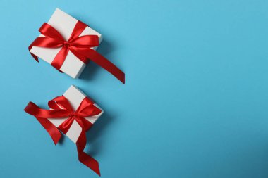 Kırmızı kurdelelere sarılı, mavi arka planda kırmızı kalplerle çevrili sevgililer günü afişi. Romantik ve şenlikli etkinlikler için ideal.