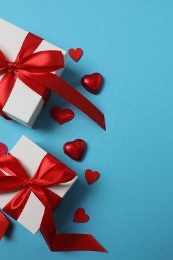 Kırmızı kurdelelere sarılı, mavi arka planda kırmızı kalplerle çevrili sevgililer günü afişi. Romantik ve şenlikli etkinlikler için ideal.