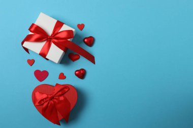 Kırmızı kurdelelere sarılı, mavi arka planda kırmızı kalplerle çevrili sevgililer günü afişi. Romantik ve şenlikli etkinlikler için ideal.