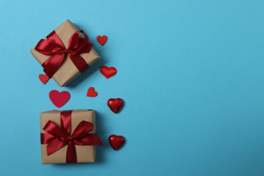 Kırmızı kurdelelere sarılı, mavi arka planda kırmızı kalplerle çevrili sevgililer günü afişi. Romantik ve şenlikli etkinlikler için ideal.