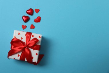 Kırmızı kurdelelere sarılı, mavi arka planda kırmızı kalplerle çevrili sevgililer günü afişi. Romantik ve şenlikli etkinlikler için ideal.