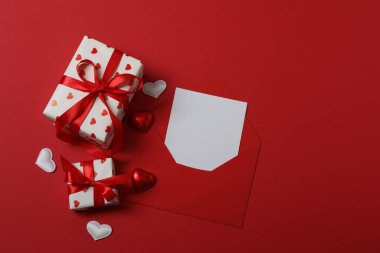 Kırmızı kurdelelere sarılı, kırmızı kalplerle çevrili hediye kutularıyla Sevgililer Günü afişi. Romantik ve şenlikli etkinlikler için ideal.