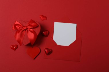 Kırmızı kurdelelere sarılı, kırmızı kalplerle çevrili hediye kutularıyla Sevgililer Günü afişi. Romantik ve şenlikli etkinlikler için ideal.