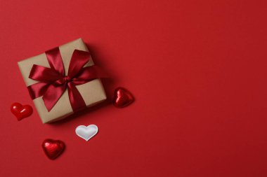 Kırmızı kurdelelere sarılı, kırmızı kalplerle çevrili hediye kutularıyla Sevgililer Günü afişi. Romantik ve şenlikli etkinlikler için ideal.