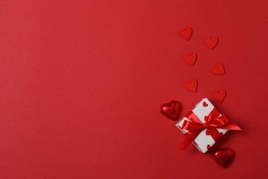 Kırmızı kurdelelere sarılı, kırmızı kalplerle çevrili hediye kutularıyla Sevgililer Günü afişi. Romantik ve şenlikli etkinlikler için ideal.