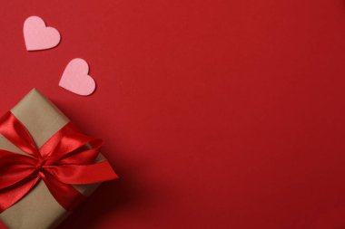 Kırmızı kurdelelere sarılı, kırmızı kalplerle çevrili hediye kutularıyla Sevgililer Günü afişi. Romantik ve şenlikli etkinlikler için ideal.