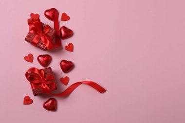 Pembe arka planda kırmızı kalplerle çevrili Sevgililer Günü afişi. Romantik ve şenlikli olaylar için mükemmel..