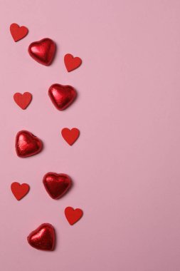 Pembe arka planda kırmızı kalplerle çevrili Sevgililer Günü afişi. Romantik ve şenlikli olaylar için mükemmel..