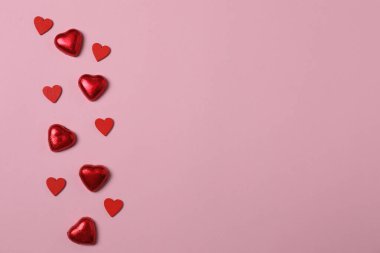 Pembe arka planda kırmızı kalplerle çevrili Sevgililer Günü afişi. Romantik ve şenlikli olaylar için mükemmel..