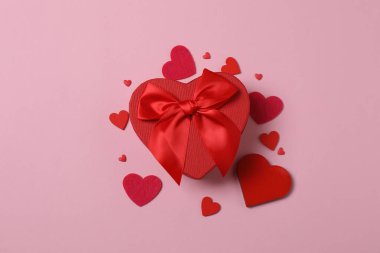 Pembe arka planda kırmızı kalplerle çevrili Sevgililer Günü afişi. Romantik ve şenlikli olaylar için mükemmel..