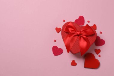 Pembe arka planda kırmızı kalplerle çevrili Sevgililer Günü afişi. Romantik ve şenlikli olaylar için mükemmel..