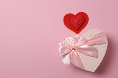 Renkli arka planda kırmızı kalplerle çevrili hediye kutularıyla Sevgililer Günü afişi. Romantik ve şenlikli olaylar için mükemmel..