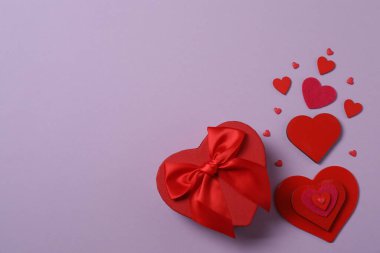 Renkli arka planda kırmızı kalplerle çevrili hediye kutularıyla Sevgililer Günü afişi. Romantik ve şenlikli olaylar için mükemmel..