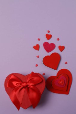 Renkli arka planda kırmızı kalplerle çevrili hediye kutularıyla Sevgililer Günü afişi. Romantik ve şenlikli olaylar için mükemmel..