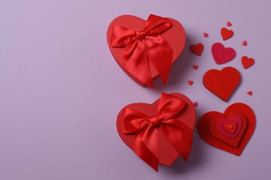 Renkli arka planda kırmızı kalplerle çevrili hediye kutularıyla Sevgililer Günü afişi. Romantik ve şenlikli olaylar için mükemmel..