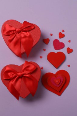 Renkli arka planda kırmızı kalplerle çevrili hediye kutularıyla Sevgililer Günü afişi. Romantik ve şenlikli olaylar için mükemmel..