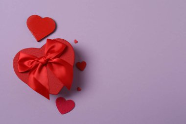 Renkli arka planda kırmızı kalplerle çevrili hediye kutularıyla Sevgililer Günü afişi. Romantik ve şenlikli olaylar için mükemmel..