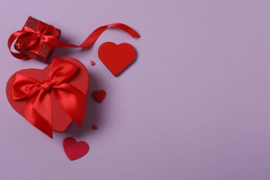 Renkli arka planda kırmızı kalplerle çevrili hediye kutularıyla Sevgililer Günü afişi. Romantik ve şenlikli olaylar için mükemmel..