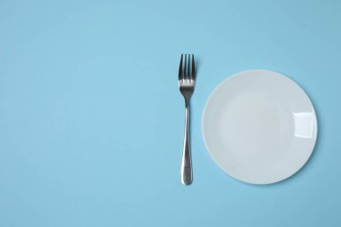 Renkli arka planda boş tabak ve çatal bıçak takımı, üst görünüm