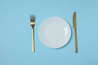 Renkli arka planda boş tabak ve çatal bıçak takımı, üst görünüm