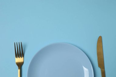 Renkli arka planda boş tabak ve çatal bıçak takımı, üst görünüm