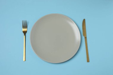 Renkli arka planda boş tabak ve çatal bıçak takımı, üst görünüm