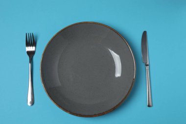 Renkli arka planda boş tabak ve çatal bıçak takımı, üst görünüm