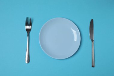 Renkli arka planda boş tabak ve çatal bıçak takımı, üst görünüm
