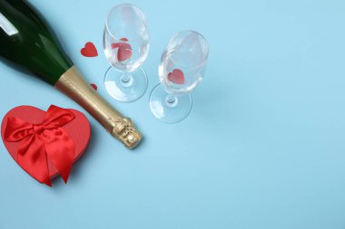 Bir şişe şampanya, iki bardak ve kupa ve hediye kutularıyla şenlik arka planı. Sevgililer gününde romantik bir randevu.