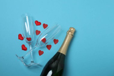 Bir şişe şampanya, iki bardak ve kupa ve hediye kutularıyla şenlik arka planı. Sevgililer gününde romantik bir randevu.