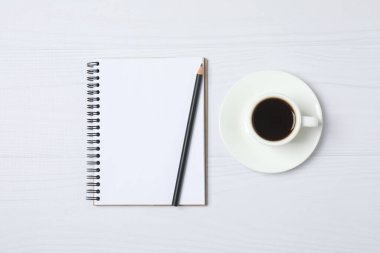 Kalem ve kahveyle masaya yaylı not defteri. Ofis kavramı. Üst görünüm.