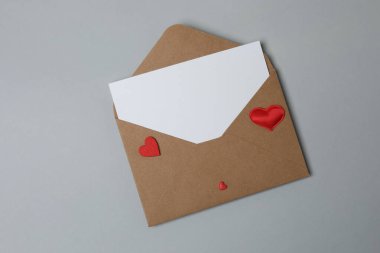 Sevgililer Günün kutlu olsun. Tebrik kartı ve gri arka planda dekoratif kalp ile zarf, üst görünüm