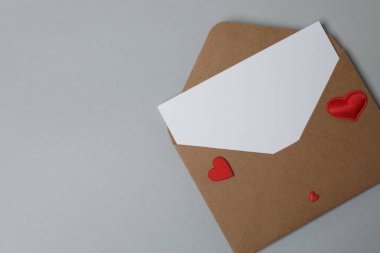 Sevgililer Günün kutlu olsun. Tebrik kartı ve gri arka planda dekoratif kalp ile zarf, üst görünüm