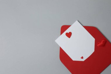 Sevgililer Günün kutlu olsun. Tebrik kartı ve gri arka planda dekoratif kalp ile zarf, üst görünüm