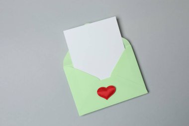 Sevgililer Günün kutlu olsun. Tebrik kartı ve gri arka planda dekoratif kalp ile zarf, üst görünüm