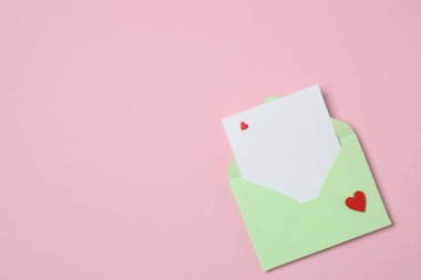 Sevgililer Günün kutlu olsun. Tebrik kartı ve pembe arka planda dekoratif kalp ile zarf, üst görünüm