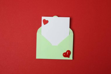 Sevgililer Günün kutlu olsun. Tebrik kartı ve kırmızı arka planda dekoratif kalp ile zarf, üst görünüm