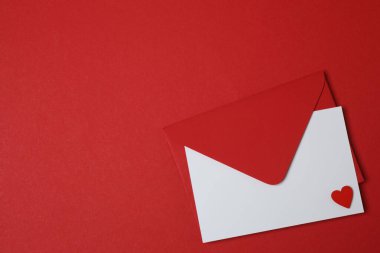 Sevgililer Günün kutlu olsun. Tebrik kartı ve kırmızı arka planda dekoratif kalp ile zarf, üst görünüm