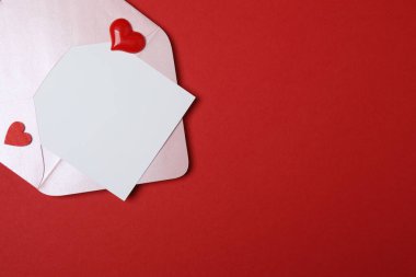 Sevgililer Günün kutlu olsun. Tebrik kartı ve kırmızı arka planda dekoratif kalp ile zarf, üst görünüm